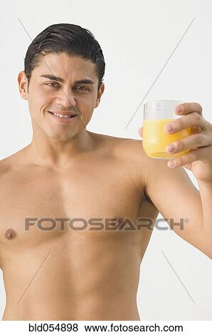 Bare-chested Hispanic man holding orange juice View Large Photo Image Stock Photo - Bare-chested Hispanic man holding orange juice. Fotosearch