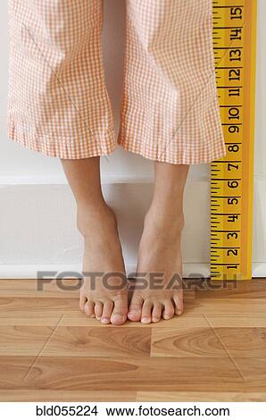 Picture - Girl standing on tiptoes next to ruler. Fotosearch