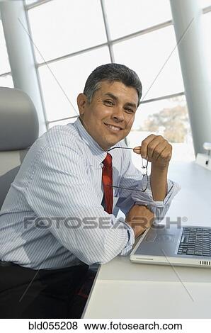 Hispanic businessman holding eyeglasses View Large Photo Image Stock Photo - Hispanic businessman holding eyeglasses. Fotosearch
