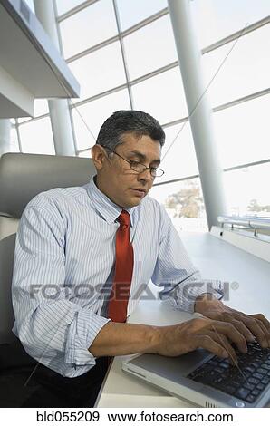 Hispanic businessman typing on laptop View Large Photo Image Stock Photo - Hispanic businessman typing on laptop. Fotosearch