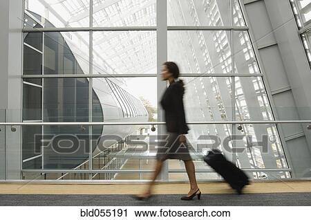 Stock Image - Hispanic businesswoman pulling suitcase. Fotosearch