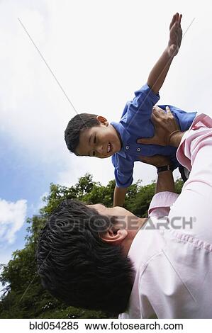 Stock Photography - Hispanic father holding son in air. Fotosearch