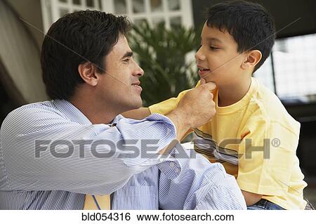 Stock Photograph - Hispanic father touching son’s chin. Fotosearch