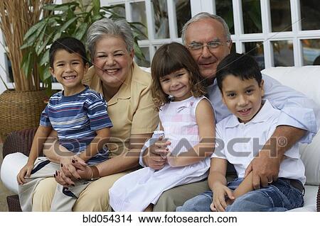 Picture - Hispanic grandparents hugging grandchildren. Fotosearch