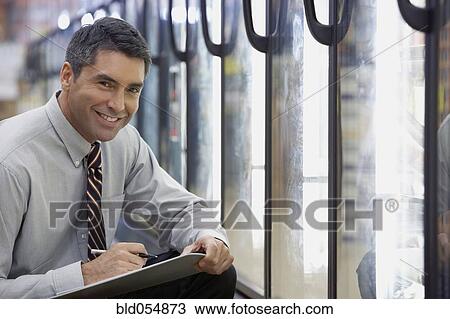 Stock Image - Hispanic grocery store manager holding clipboard. Fotosearch