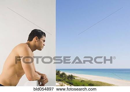 Stock Photo - Hispanic man leaning on balcony railing. Fotosearch
