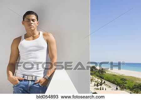 Stock Image - Hispanic man leaning on balcony wall. Fotosearch