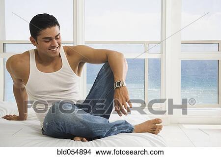 Hispanic man sitting on bed View Large Photo Image Picture - Hispanic man sitting on bed. Fotosearch