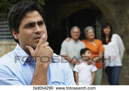 Hispanic man thinking with family in background View Large Photo Image Stock Image - Hispanic man thinking with family in background. Fotosearch