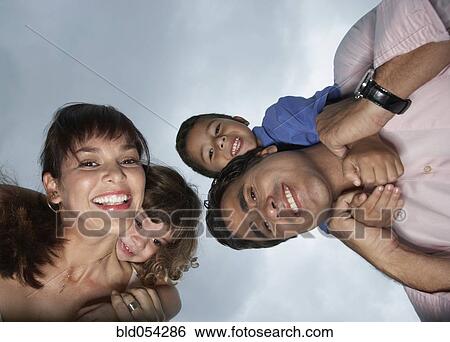 Stock Photograph - Hispanic parents giving children piggy back rides. Fotosearch