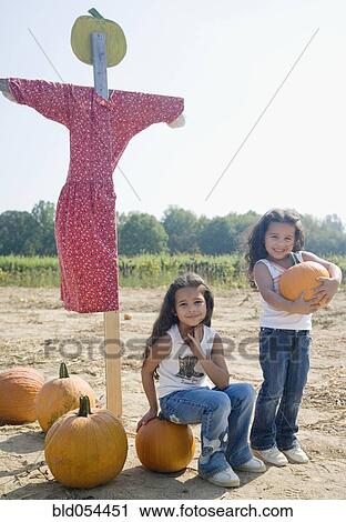 Hispanic sisters with pumpkins and scarecrow View Large Photo Image Stock Image - Hispanic sisters with pumpkins and scarecrow. Fotosearch