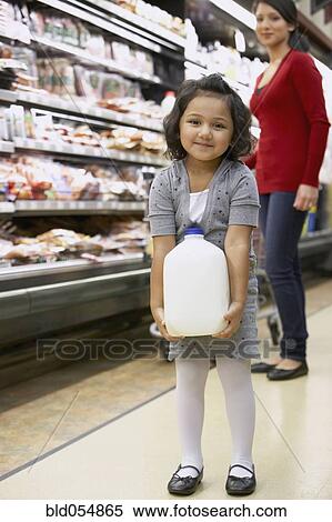 Stock Photography - Indian girl carrying milk in grocery store. Fotosearch