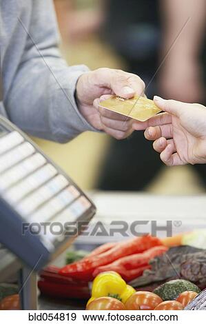 Stock Photo - Man paying with credit card at grocery store. Fotosearch