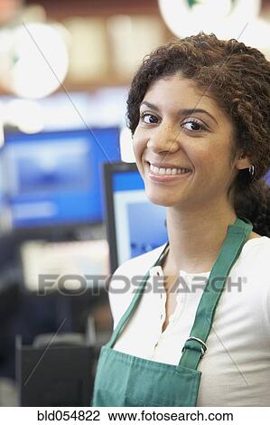Stock Image - Mixed Race cashier wearing apron. Fotosearch