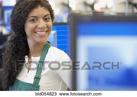 Stock Image - Mixed Race cashier wearing apron. Fotosearch