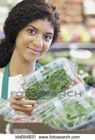 Stock Image - Mixed Race clerk in grocery store. Fotosearch