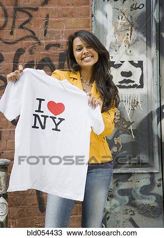 Stock Image - Mixed Race woman holding t-shirt. Fotosearch