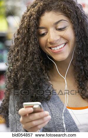 Mixed Race woman listening to mp3 player View Large Photo Image Stock Photo - Mixed Race woman listening to mp3 player. Fotosearch
