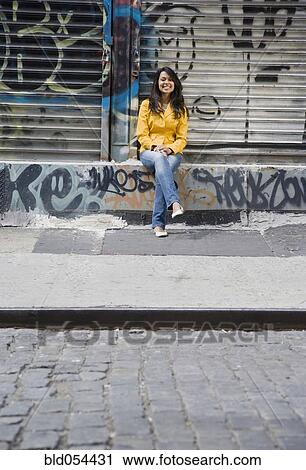 Mixed Race woman sitting on urban sidewalk View Large Photo Image Stock Image - Mixed Race woman sitting on urban sidewalk. Fotosearch