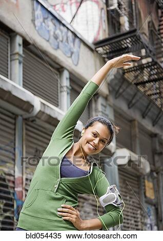 Stock Photography - Mixed Race woman stretching in urban area. Fotosearch