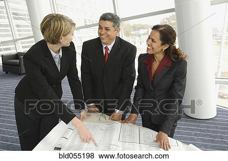 Multi-ethnic businesspeople discussing blueprints View Large Photo Image Stock Photo - Multi-ethnic businesspeople discussing blueprints. Fotosearch