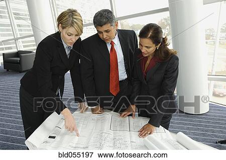 Multi-ethnic businesspeople looking at blueprints View Large Photo Image Stock Photo - Multi-ethnic businesspeople looking at blueprints. Fotosearch