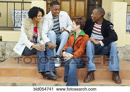 Stock Image - Multi-ethnic couples sitting on porch steps. Fotosearch
