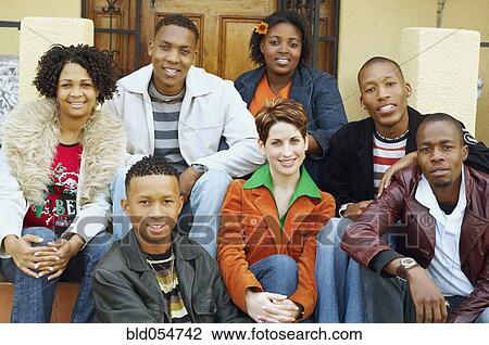 Stock Image - Multi-ethnic friends sitting on porch steps. Fotosearch
