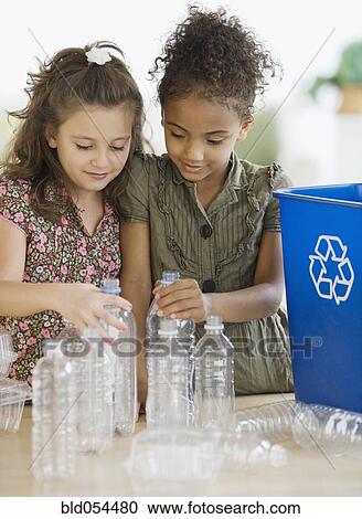Stock Image - Multi-ethnic girl recycling bottles. Fotosearch