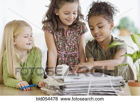 Multi-ethnic girls bundling newspapers View Large Photo Image Stock Photo - Multi-ethnic girls bundling newspapers. Fotosearch