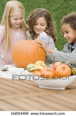 Multi-ethnic girls carving pumpkin View Large Photo Image Stock Photo - Multi-ethnic girls carving pumpkin. Fotosearch