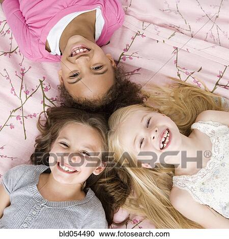 Multi-ethnic girls laying on bed View Large Photo Image Stock Image - Multi-ethnic girls laying on bed. Fotosearch