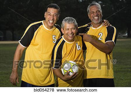 Stock Photo - Multi-ethnic men holding soccer ball. Fotosearch