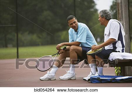 Multi-ethnic men talking on tennis court View Large Photo Image Picture - Multi-ethnic men talking on tennis court. Fotosearch
