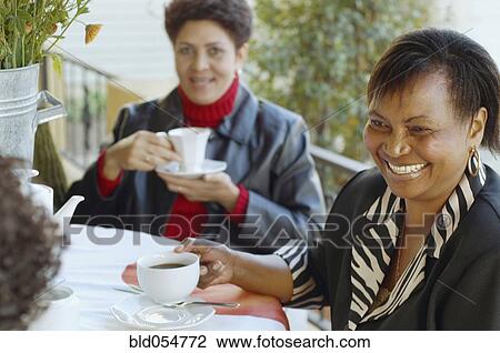 Stock Image - Multi-ethnic women having coffee outdoors. Fotosearch