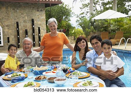 Stock Image - Multi-generational Hispanic family eating outdoors. Fotosearch