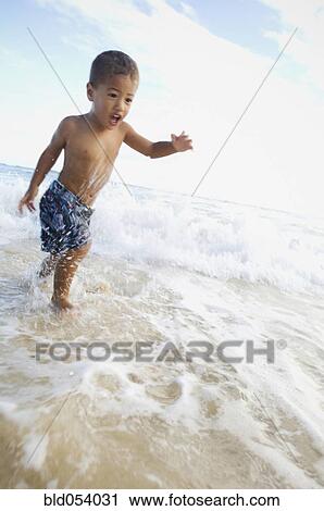 Pacific Islander boy wading in ocean surf View Large Photo Image Stock Image - Pacific Islander boy wading in ocean surf. Fotosearch