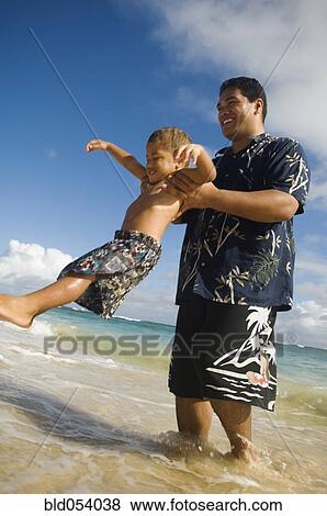 Stock Photo - Pacific Islander father and son playing at beach. Fotosearch
