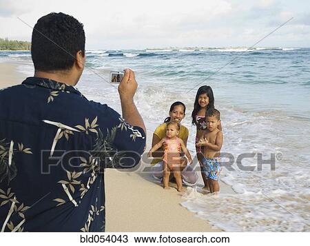 Stock Image - Pacific Islander father taking photograph of family. Fotosearch