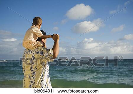 Stock Image - Pacific Islander father with son on shoulders at beach. Fotosearch