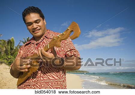 Stock Photo - Pacific Islander man playing instrument at beach. Fotosearch
