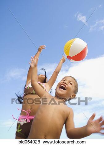 Stock Photo - Pacific Islander siblings playing with beach ball. Fotosearch