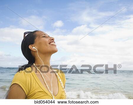 Picture - Pacific Islander woman listening to mp3 player. Fotosearch