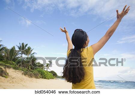 Pacific Islander woman with arms raised at beach View Large Photo Image Stock Photograph - Pacific Islander woman with arms raised at beach. Fotosearch