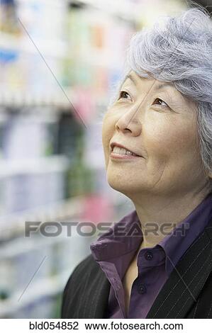 Stock Image - Senior Asian woman looking up. Fotosearch
