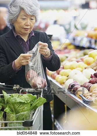 Senior Asian woman shopping for produce View Large Photo Image Stock Photo - Senior Asian woman shopping for produce. Fotosearch