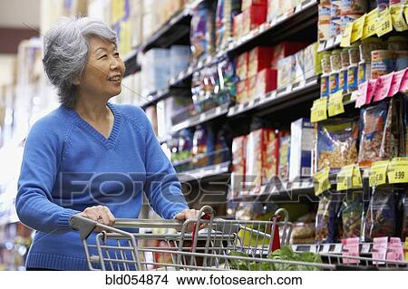 Picture - Senior Asian woman shopping in grocery store. Fotosearch