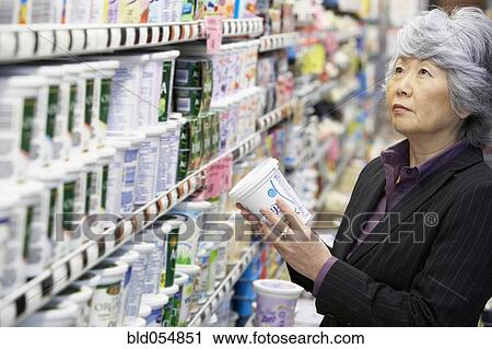 Stock Image - Senior Asian woman shopping in grocery store. Fotosearch