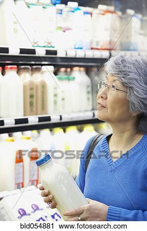 Stock Image - Senior Asian woman shopping in grocery store. Fotosearch