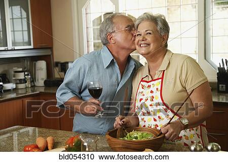 Stock Image - Senior Hispanic man kissing wife. Fotosearch